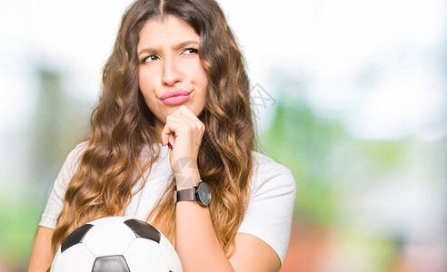 年轻的成年女拿着足球认真的脸思考问题图片