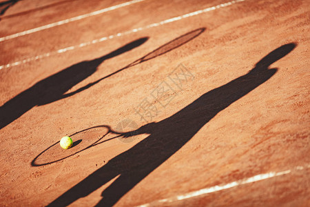 网球和网球运动员在红土场上的影子图片