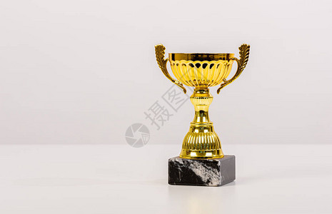 浅灰色背景上带有大理石底座的金色奖杯图片