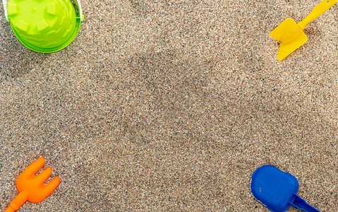 沙子中的塑料儿童玩具家庭度假概念顶视背景图片