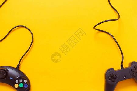黄色背景上的两个有线游戏手柄或视频游戏控制器图片
