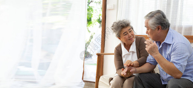 亚洲老年退休夫妇手牵在家照顾阿尔茨海默病或患图片