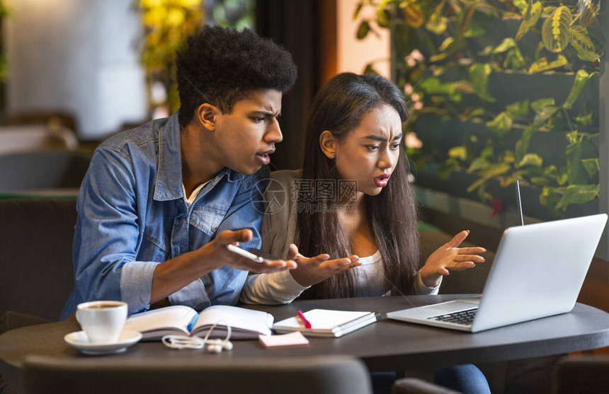 什么是错的愤怒的混合种族学生夫妇急忙地看着笔记本电脑屏幕图片