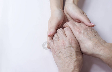年长妇女的手握在照顾老年的轻妇女的手中图片
