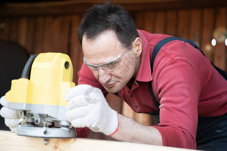 工匠在乡间别墅车间用铣削工具加工木制工件用铣削木工机加工天然木梁图片