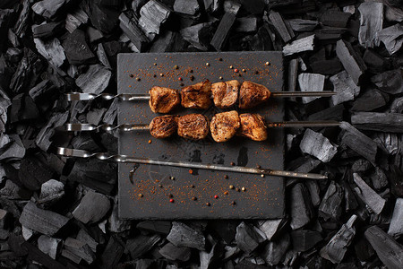 烤串上的烤羊肉串石板上的两份烤肉和一根空串木炭图片