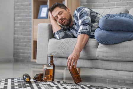 男人在家里喝啤酒酗酒的概图片