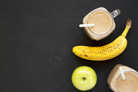 健康的香蕉苹果冰沙在黑色背景的玻璃罐中图片