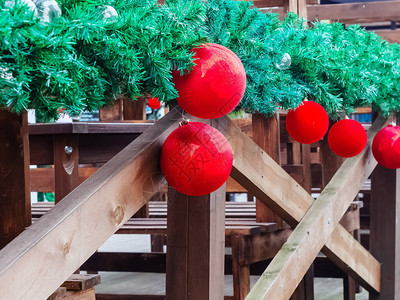 红色圣诞球挂在木栏杆上的绿色云杉树枝上图片