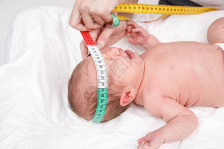 儿科医生检查两周大的婴儿医生使用卷尺检查新生儿的头部大小新图片