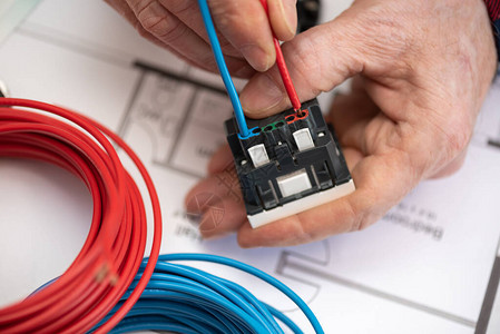 电工手将电线连接到电源插座图片