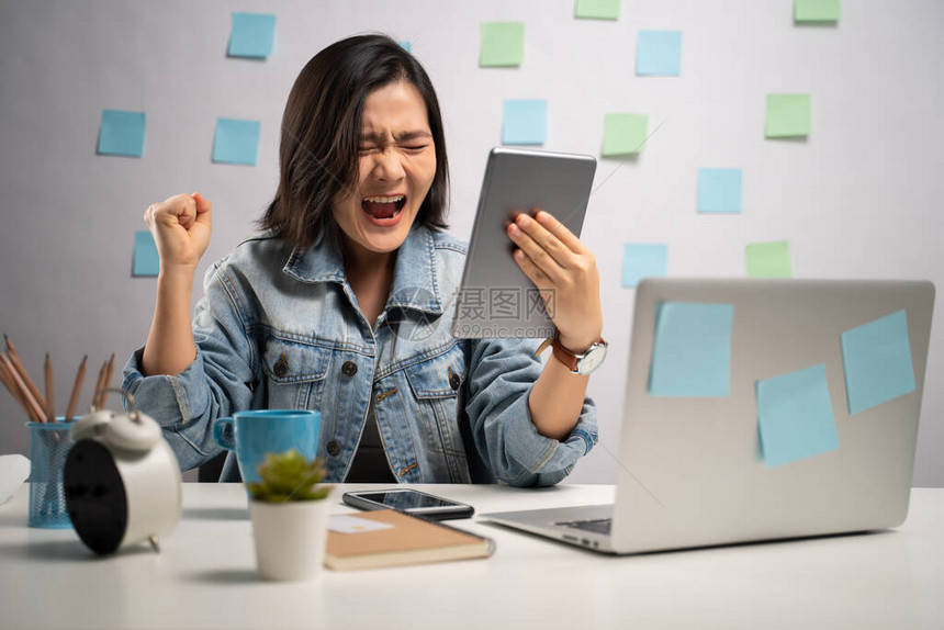 亚洲妇女愤怒地看着平板电脑看新闻和在家庭办公室大喊叫WFH在家工作图片