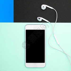 蓝色黑色和柔的蓝色背景上的白色智能手机和耳机图片