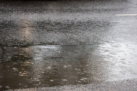 在城市白天下雨时在沥青路上筑水坑有选择弄湿高清图片素材