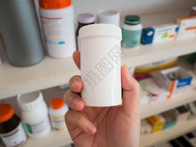 药剂师手持药瓶在药房架上的特写药房图片