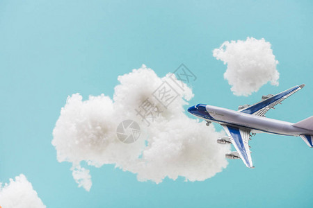 玩具飞机在白毛云中飞行由蓝色的孤立背景图片