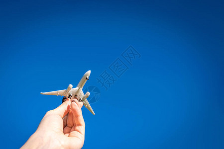 手中的白色旅行飞机在明亮的阳光空气背景下飞行图片