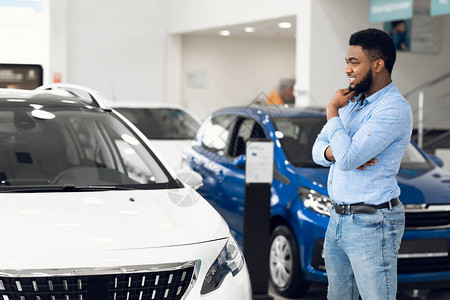 购买汽车欢乐的非洲裔美国人在自动常设经销商竞技展示室中寻找自己生活的图片