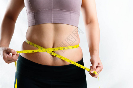 年轻女用卷尺测量她过多的腹部脂肪腰部图片