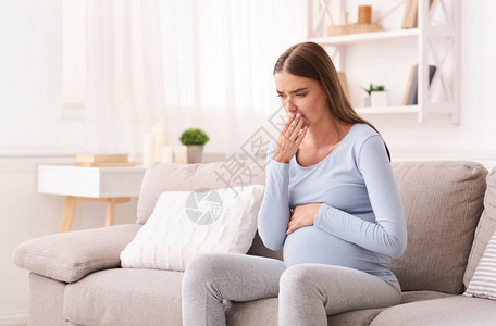 早孕生病了孕妇在室内索法岛坐着感觉不舒服的嘴唇怀图片