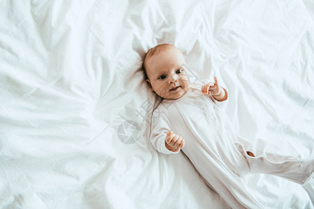 穿着白礼服的可爱婴儿躺在家图片