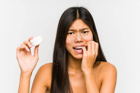 年轻女人拿着湿润剂孤立的咬指甲紧张和焦虑不安图片