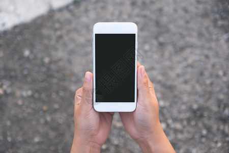 手持白色手机带街道背景的空白黑屏幕的顶部图背景图片