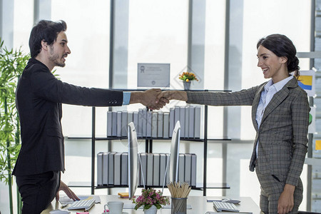 穿着西装握手的快乐商务专业人士在办公室欢迎同事会议中的商业伙伴女商图片