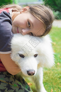 拥抱狗品种萨摩耶的快乐女孩图片