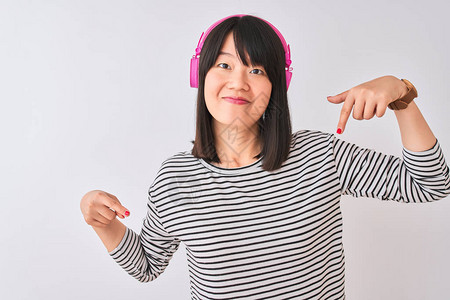 女人用粉色耳机在孤立的白色背景上听音乐图片