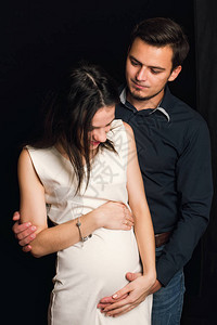 怀着幸福的怀孕女孩和男人拥抱肚子图片