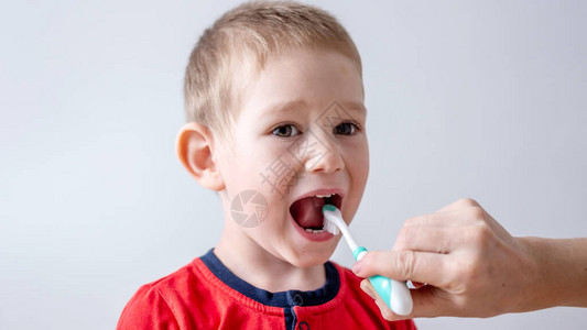 蹒跚学步的孩子在父母的帮助下刷牙学习儿童牙科保健背景图片