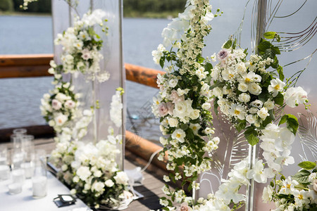 关闭与白色透明屏幕和鲜花和蜡烛的婚礼带羽毛和白玫瑰的两个屏风的图片