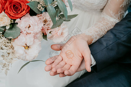 新娘和新郎的手在婚礼花束的背图片