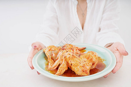 大厨手上盘子上的生鸡翅韩国面糊蜂蜜大蒜豆酱和香料的洋图片