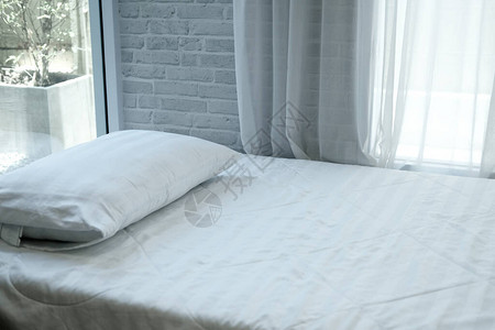 床垫上的白色枕头透过明的窗帘可以看到图片