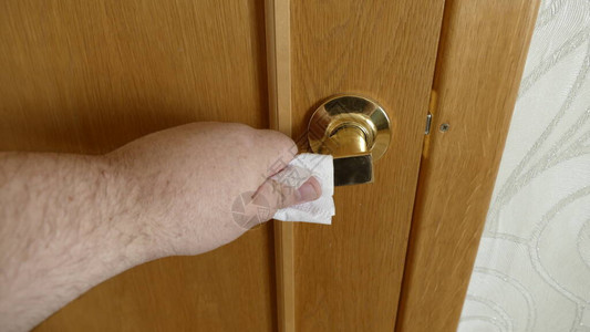 男人通过卫生纸抓住门把手以保护免受冠图片