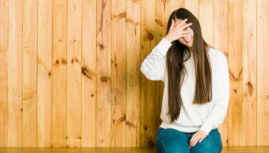 坐在木制地方的年轻女人手指对着摄像机眨眼图片