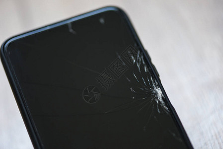 木背景上的智能手机碎玻璃屏幕手机碎屏等待维修店概念图片