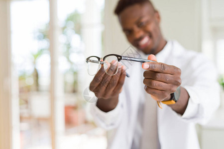 非洲裔美国眼镜男在光学店里拿着眼镜并向顾客展示眼镜图片