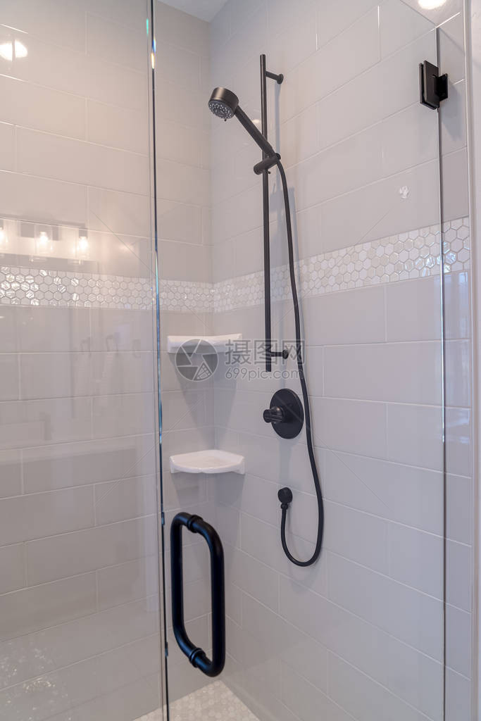 浴室隔间配有黑色淋浴装置和白色瓷砖墙上的肥皂盘在这个洗手间内还可以看到带有黑色把手图片