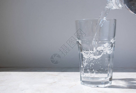 清洁水流从瓶子倒入玻璃杯中图片