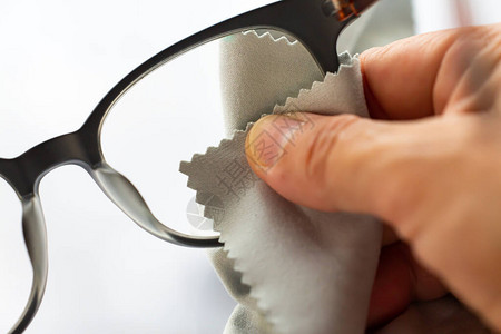 女右手用灰色微纤维清洁布清洁近视或近视眼镜图片