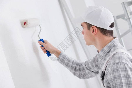 年轻画家在翻修或建筑期间绘画白色图片