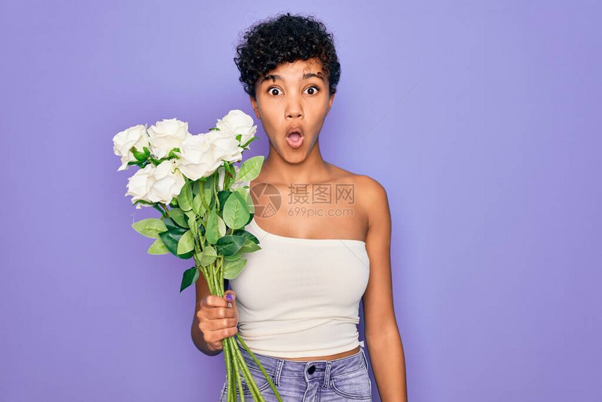 美丽的非洲裔美国黑人女拿着一束紫色背景上的白花图片