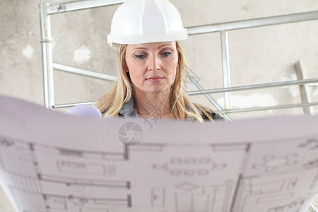 女建筑师或建筑工程师在背景脚手架的建筑工地内阅图片