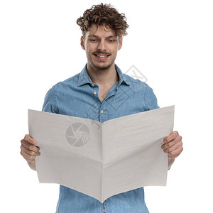 快乐的年轻人在丹尼姆衬衫阅读报纸背景图片