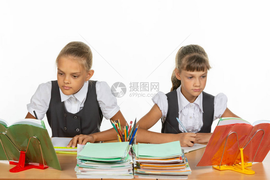 两位女学生坐在书桌旁看教科书坐