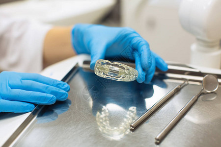 牙医女手在牙科诊所手持可拆卸的正畸牙齿对齐图片