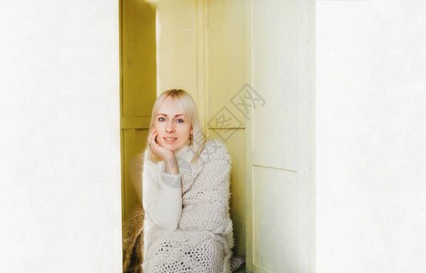 身着长白色羊毛衫的金发年轻女子坐在柜子图片